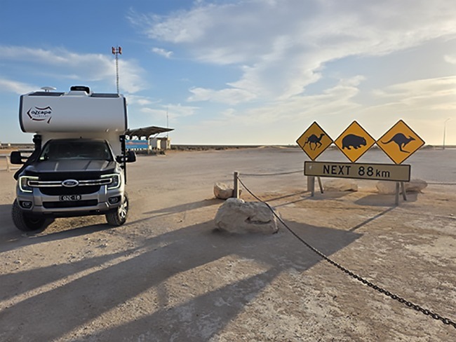 Outback setting. Ozcape Woondabaa slide-on next to traffic signs warning of camels, wombats and kangaroos